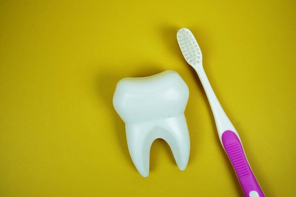 Toothbrush and Tooth dental hygiene concept top view on yellow background