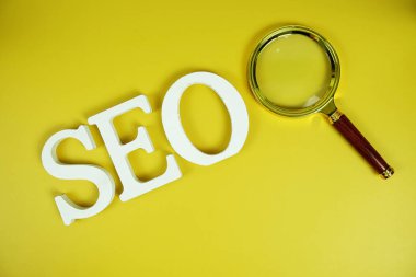 Sarı zemin üzerinde büyüteç bulunan Seo sözcükleri (Arama Motoru İyimsemesi) harfleri