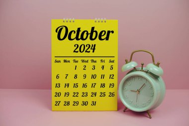Pembe zemin üzerinde çalar saat ile planlama ve yönetim konsepti için Ekim 2024 aylık takvim