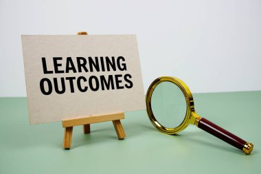 Kağıt üzerinde yeşil arkaplanda büyüteç bulunan Çıktılar metni öğreniliyor