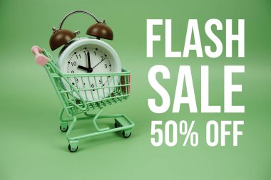 Yeşil arka planda alarm saati olan tramvay alışveriş arabasıyla% 50 indirimli mesaj.