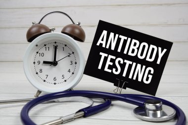 Antikorlar kağıt kart üzerinde steteskop ve ahşap zemin üzerinde alarm saati ile metin denemesi yapıyor