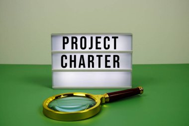 LED ışıkkutusu üzerinde yeşil zemin üzerinde büyüteç bulunan Proje Sözleşmesi metni