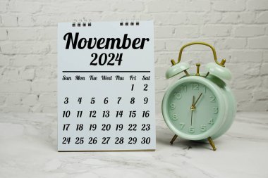 Mermer zemin üzerinde çalar saat ile planlama ve yönetim konsepti için Kasım 2024 aylık takvim