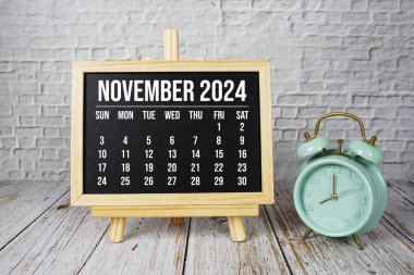 Kasım 2024 Ahşap zemin üzerinde aylık takvim ve alarm saati