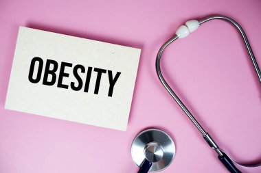 Pembe arka planda steteskoplu obezite metni, sağlıklı ve sağlıklı olma kavramı
