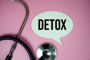 Steteskoplu detoks metni ve pembe arka planda büyüteç, sağlıklı ve sağlıklı olma kavramı