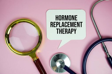 Hormon Değiştirme Terapisi metni steteskop ve büyüteçle pembe arka plan, sağlıklı ve sağlıklı yaşam kavramı