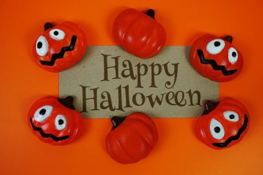 Turuncu arka planda balkabağı süslemesi olan kağıt üzerinde mutlu Cadılar Bayramı metinleri