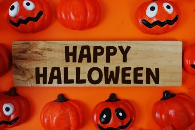 Turuncu arka planda balkabağı süslemesi olan kağıt üzerinde mutlu Cadılar Bayramı metinleri