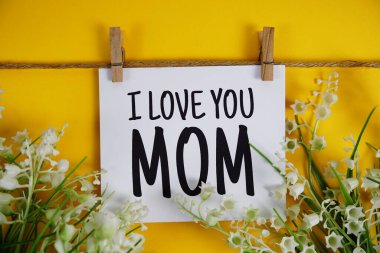 Sarı arka planda çiçek açan kartın üzerindeki Anneler Günün kutlu olsun.