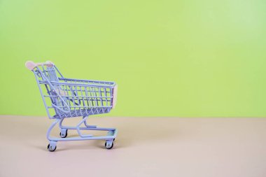 Mini Trolley alışveriş arabası. Pembe ve yeşil arka planda metin için yeri var.