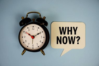 Why now? text on speech bluble with alarm clock top view on blue background clipart