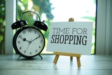 Pencerenin arka planında resim sehpası ve alarm saati olan kağıt alışverişi zamanı