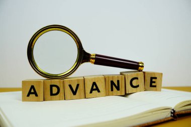 Tahta bloklar alfabe harfli büyüteç sarı arkaplanda ADVANCE metin mesajı