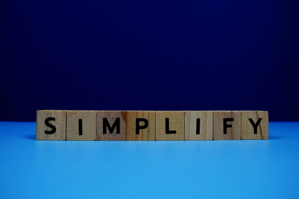 SimplifySimplify with wooden blocks alphabet letters on blue background