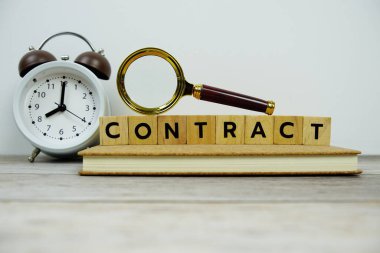 Tahta bloklar alfabe harfleriyle büyüteç ve alarm saati Tahta zemin üzerinde ContracACT metin mesajı