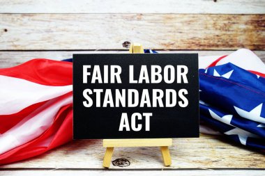 Fair Labor Standards Act text messege with USA flag on wooden background clipart