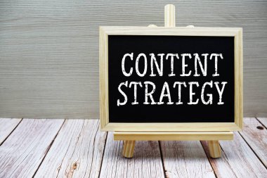 İçerik Stratejisi metni tahta zemin üzerinde sehpası ile karatahtaya yazılmış