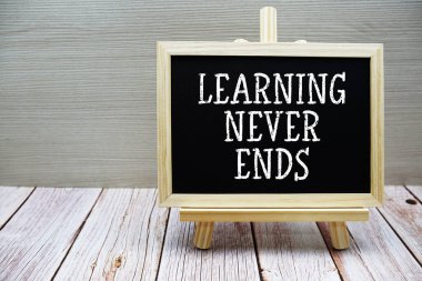 Öğrenme Ahşap arkaplan sehpası ile karatahtaya yazılmış metni asla bitirmez