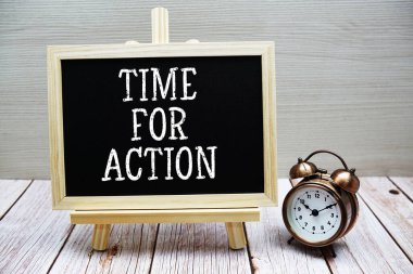 Tahtaya yazılmış ve ahşap zemin üzerinde alarm saati olan Eylem metni zamanı