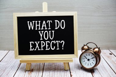 Ne bekliyorsunuz? Tahtaya yazılan ve ahşap arkaplanda alarm saati olan metin
