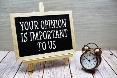 Düşünceleriniz bizim için çok önemli tahtaya yazılmış ve ahşap zemin üzerinde alarm saati var.