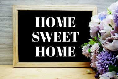 Tahtadaki Home Sweet Home metni ahşap arka planda çiçek buketi süslemesi
