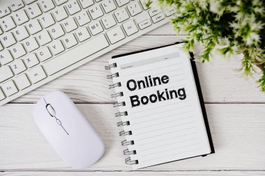 Not defterinde klavye ve ahşap arka planda optik fare ile çevrimiçi rezervasyon metni