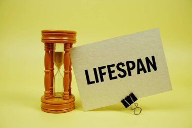 Lifespan text message on paper card with Hourglass on yellow background clipart