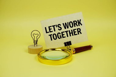 Let's Work Together text message on paper card with magnifying glass on yellow background clipart