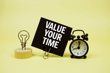 Sarı arkaplanda alarm saati olan yapışkan notta Zaman Mesajınıza Değer Verin