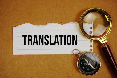 Kağıt üzerinde çeviri metni pusula ile yırtılmış ve kağıt işçiliği arka planında büyüteç