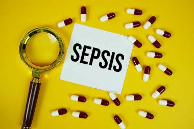 İlaç kapsülüyle sepsis metni ve sarı arka planda büyüteç.