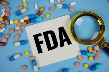 FDA - Gıda ve İlaç İdaresi mavi zemin üzerinde ilaç ve büyüteç içeren yapışkan not kağıdı metni
