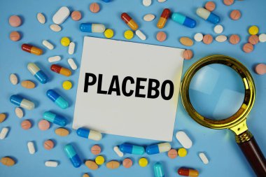 Mavi zemin üzerinde ilaç ve büyüteç bulunan yapışkan not kağıdı üzerindeki plasebo metin