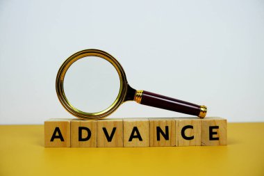 Tahta bloklar alfabe harfli büyüteç sarı arkaplanda ADVANCE metin mesajı