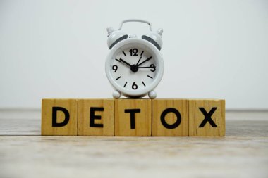Tahta bloklar alfabe harfleri ve ahşap zemin üzerinde çalar saat ile Detox zamanı