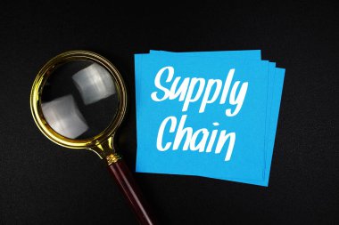 Tedarik zinciri metni yapışkan notta ve büyüteçle siyah arkaplanda