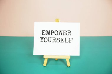 Empower yourself text message on paper card with wooden easel clipart