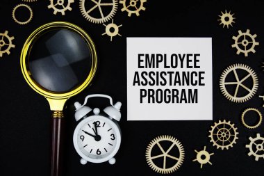 Employee Assistance Program text message on sticky note with magnifying glass and alarm clock on black background clipart