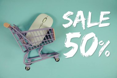 % 50 indirimli indirimli alışveriş, alışveriş arabası ve mavi arka planda optik fare.