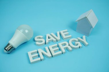 Ev modeli ve mavi arkaplanda LED ampulleri, tasarruf ve çevre dostu kavram içeren Enerji alfabesi harflerini kaydet