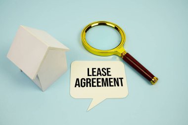 Yapışkan notta, büyüteç ve mavi arka planda ev modeli içeren kira sözleşmesi metni