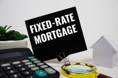 Ev modeli, hesap makinesi ve ahşap zemin üzerindeki büyüteçle sabitlenmiş ipotek mesajı