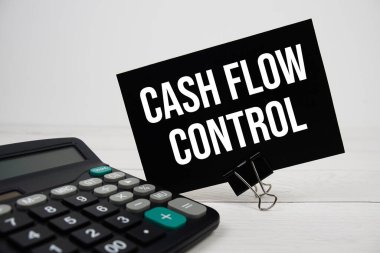 Tahta zemin üzerinde hesap makinesi olan yapışkan notta Cash Flow Control metin iletisi