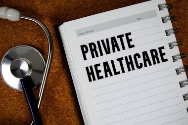 Kağıt üzerinde steteskoplu özel sağlık metni mantar kaplama arka planında yatıyordu