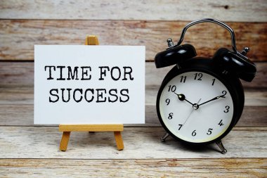 Kağıt üzerine yazılmış ve ahşap arkaplanda alarm kopyası olan Başarı metni zamanı