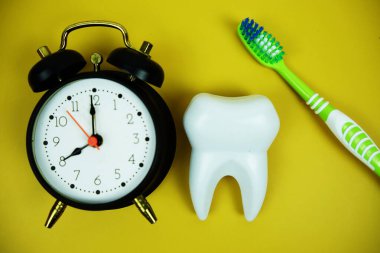 Diş fırçası ve beyaz diş fırçası modeli sarı arka planda alarm saati diş hijyeni kavramı