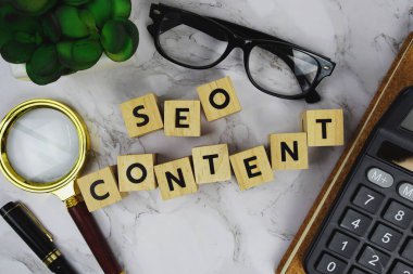 Tahta bloklar alfabe harfleriyle SEO İçeriği ve mermer zemin üzerinde büyüteç ve hesap makinesi